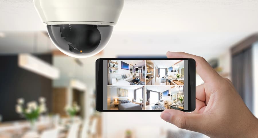 Homeowner holding smartphone with video feed from security cameras